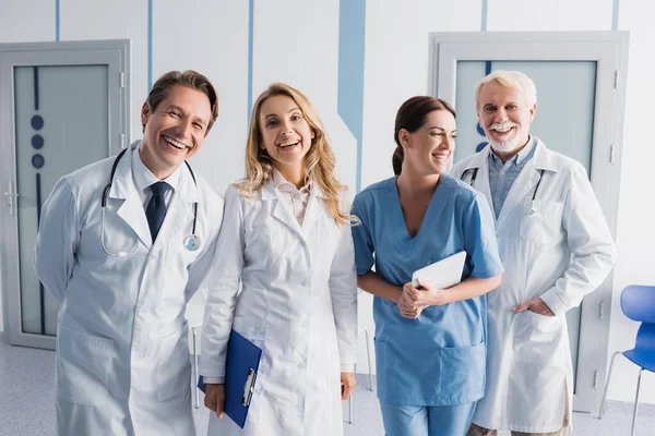 Excited hospital staff with equipment and digital tablet in clinic — Stock Photo