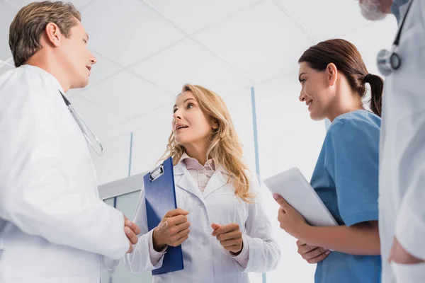 Enfoque selectivo de médicos y enfermeras con tableta digital hablando en clínica - foto de stock