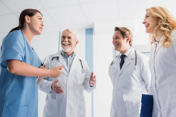 Enfoque selectivo de los médicos mirando a la enfermera con tableta digital mientras habla en la clínica — Stock Photo