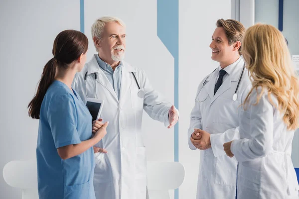 Selective focus of senior doctor talking with colleagues in hospital — Stock Photo