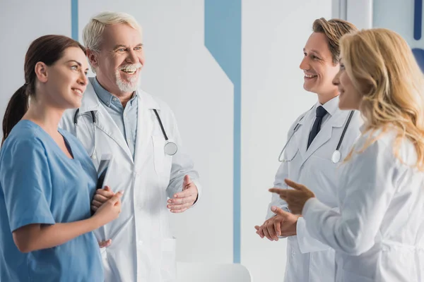 Selective focus of doctors in white coats and nurse with digital tablet talking in hospital — Stock Photo