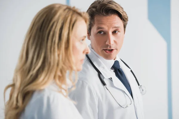 Concentration sélective du médecin regardant un collègue tout en parlant à la clinique — Photo de stock
