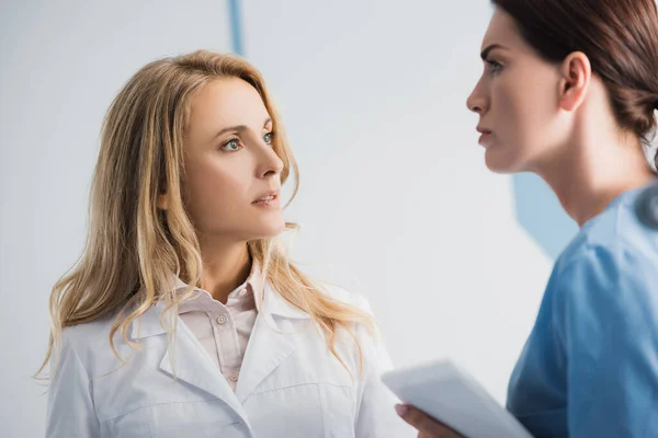 Selective focus of doctor looking at pensive nurse with digital tablet in clinic — Stock Photo