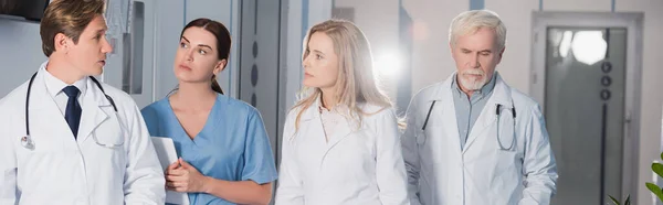 Imagem panorâmica do médico conversando com colegas e enfermeira com tablet digital no hospital — Fotografia de Stock