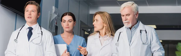 Horizontal crop of doctor pointing with finger near colleagues and nurse with digital tablet — Stock Photo