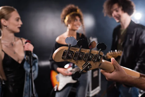 KYIV, UCRANIA - 25 de agosto de 2020: Músico sosteniendo la guitarra eléctrica con miembros borrosos de la banda de rock en el fondo - foto de stock