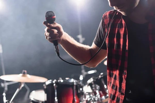 Vue recadrée du chanteur avec microphone avec kit tambour flou sur fond — Photo de stock
