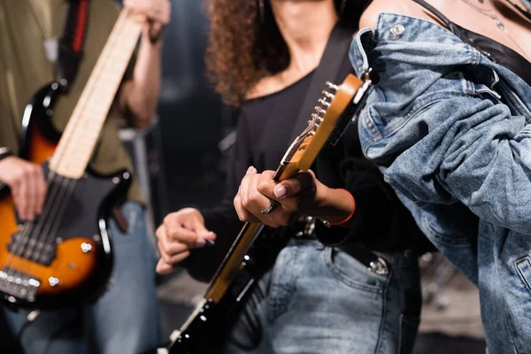 KYIV, UCRANIA - 25 de agosto de 2020: Vista recortada del músico de la banda de rock con guitarristas borrosos en el fondo - foto de stock