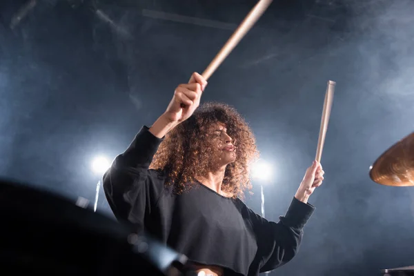 Rock band musician with drumsticks playing on cymbal on blurred foreground — Stock Photo