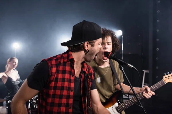 KYIV, UCRAINA - 25 AGOSTO 2020: Musicisti rock band che urlano in microfono con batterista sfocato sullo sfondo — Foto stock