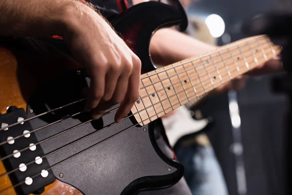 KYIV, UCRANIA - 25 de agosto de 2020: Vista recortada del músico de la banda de rock tocando la guitarra eléctrica sobre un fondo borroso - foto de stock