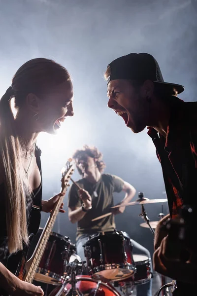 KYIV, UKRAINE - AUGUST 25, 2020: Rock band singers with electric guitars shouting with blurred drummer on background — Stock Photo
