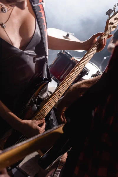 KYIV, UKRAINE - 25 AOÛT 2020 : Femme touchant des cordes de guitare debout près de la batterie avec un guitariste flou au premier plan — Photo de stock