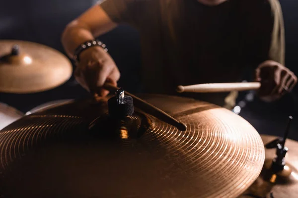 Vista recortada de pratos de metal com músico desfocado com baquetas no fundo — Fotografia de Stock