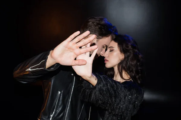 Sexy young adult couple closing camera with hands, while standing together with closed eyes on blurred background — Stock Photo