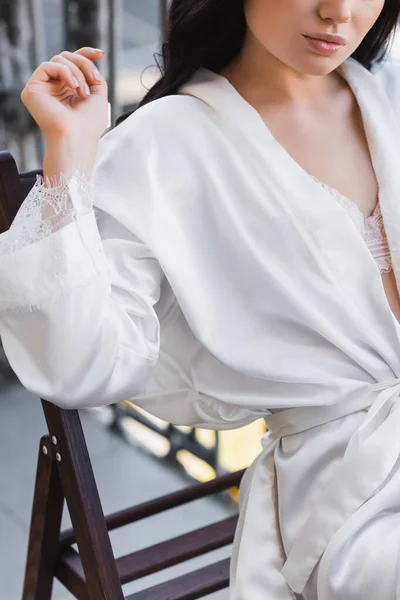 Vue partielle de la femme en robe blanche assise sur la chaise — Photo de stock
