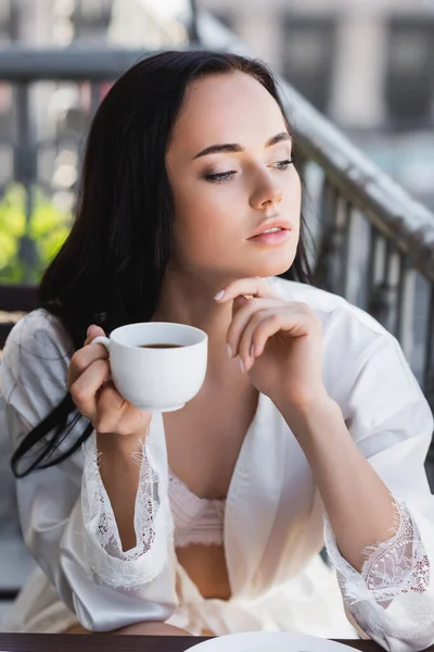 Bella donna bruna in accappatoio bianco bere caffè sul balcone — Foto stock
