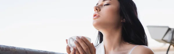 Beautiful brunette woman enjoying drinking coffee with closed eyes, horizontal banner — Stock Photo