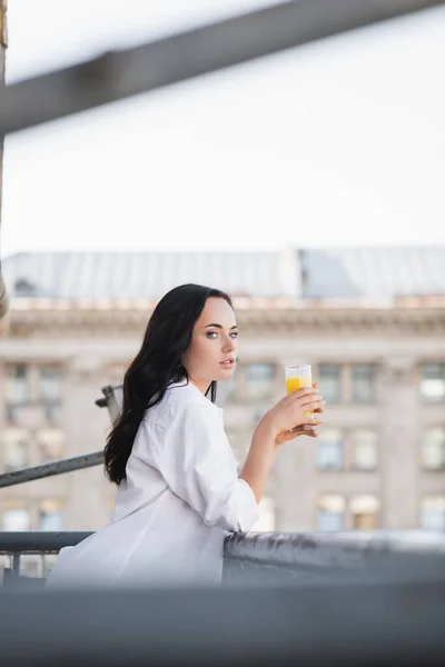 Vue latérale de la femme brune buvant du jus d'orange — Photo de stock