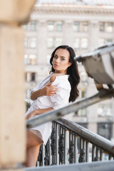 Donna in camicia bianca in posa sul balcone e mostrando spalla nuda — Foto stock