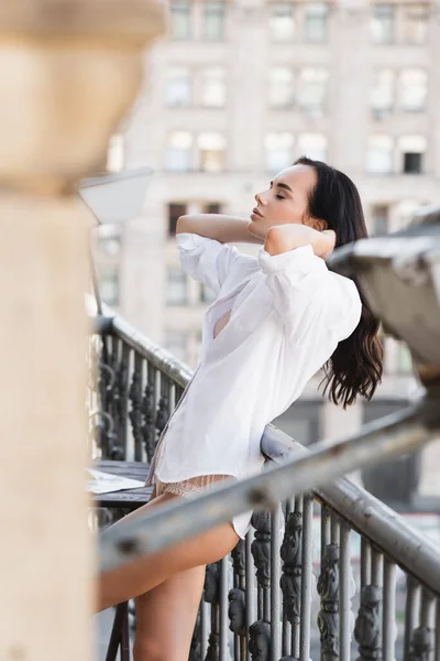 Femme en chemise blanche posant sur le balcon — Photo de stock