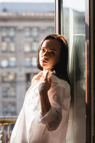 Brunette woman in white shirt leaning on window — Stock Photo