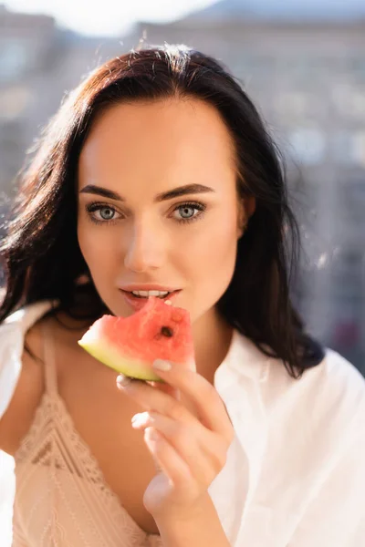 Portrait de femme brune en sous-vêtements beige et chemise blanche mangeant pastèque — Photo de stock