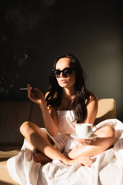 Sexy brune femme couverte de blanc feuille fumer cigarette et boire du café — Photo de stock