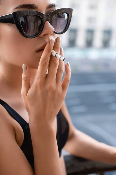 Sexy young woman in black underwear smoking cigarette on balcony — Stock Photo