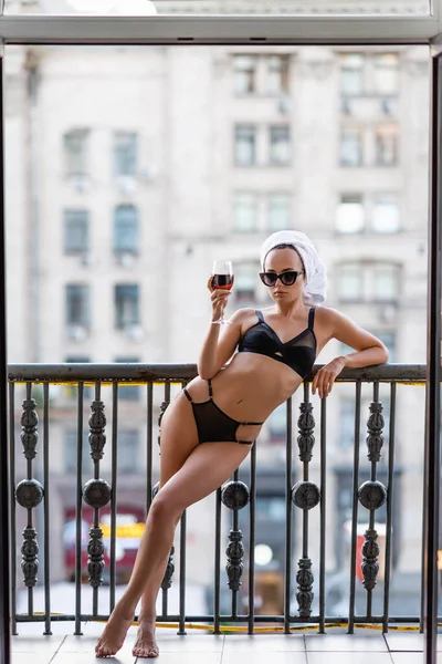 Jovem sexy em roupa interior preta com toalha na cabeça bebendo vinho tinto na varanda — Fotografia de Stock