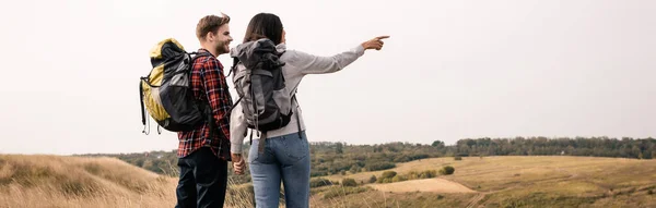African american hiker pointing with finger while holding hand of boyfriend outdoors, banner — Stock Photo