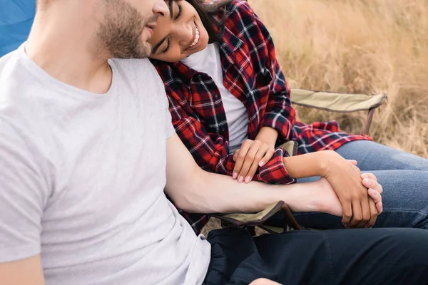 Smiling african american woman holding hand of boyfriend during camping on lawn — Stock Photo