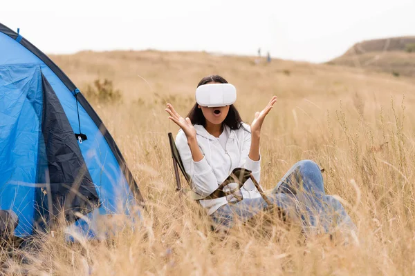 Aufgeregte Afroamerikanerin benutzt Kopfhörer in Zeltnähe auf Wiese — Stockfoto