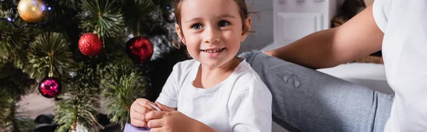 Plan panoramique de fille regardant loin près de pin festif à la maison — Photo de stock