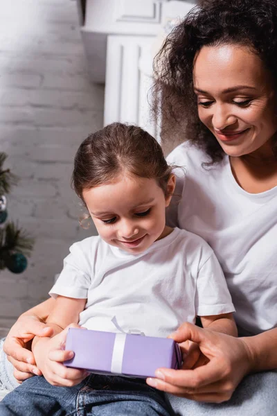 Mother hugging daughter with gift box at home — Stock Photo
