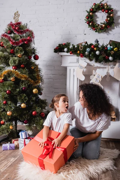 Mutter und Tochter schauen sich in der Nähe von Geschenkboxen zu Hause an — Stockfoto