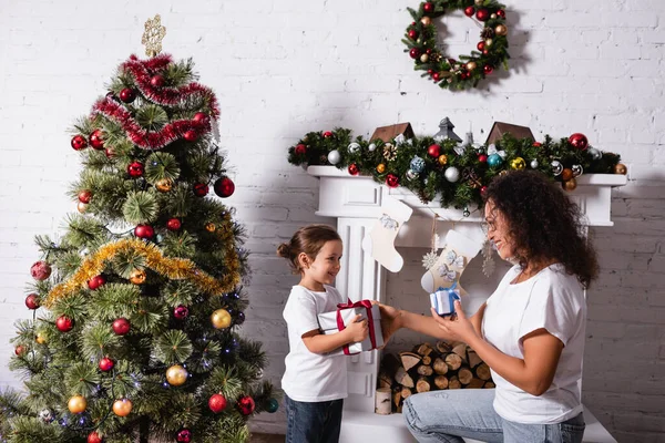 Seitenansicht von Mutter und Tochter mit Geschenken, die sich zu Hause anschauen — Stockfoto