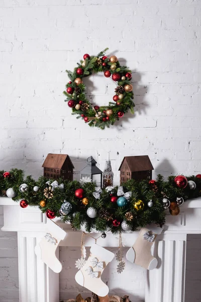 Christmas wreath above fireplace decorated with christmas balls and stockings — Stock Photo