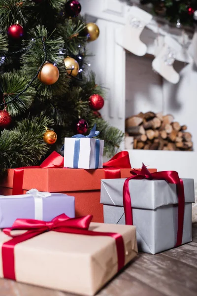 Selective focus of gift boxes near pine and fireplace with christmas stockings — Stock Photo