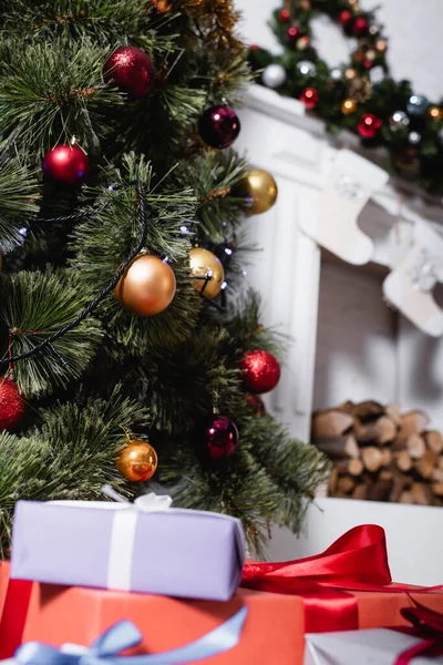 Selective focus of gift boxes near decorated pine with christmas balls — Stock Photo
