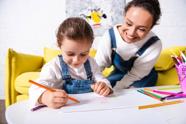 Filha desenho com lápis de cor perto da mãe em casa — Fotografia de Stock