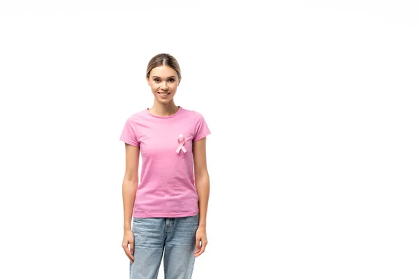 Молодая женщина в розовой футболке с лентой информированности о раке молочной железы смотрит на камеру, изолированную на белом — стоковое фото