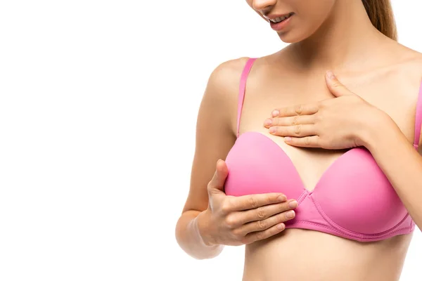 Vista recortada de la mujer joven en sujetador rosa tocando mama aislado en blanco, concepto de cáncer de mama - foto de stock