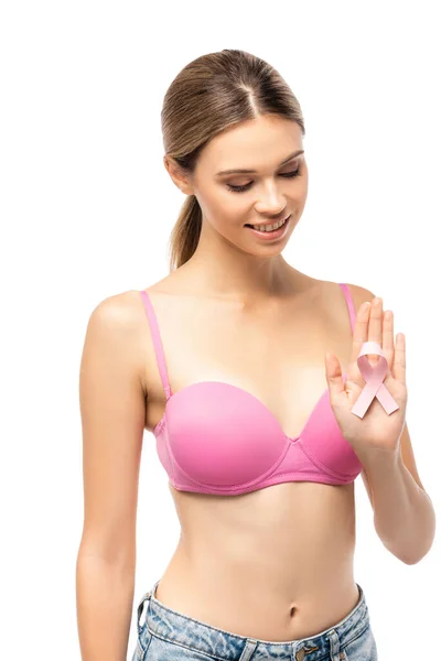 Mujer joven en sujetador mirando cinta rosa de conciencia de cáncer de mama aislado en blanco - foto de stock