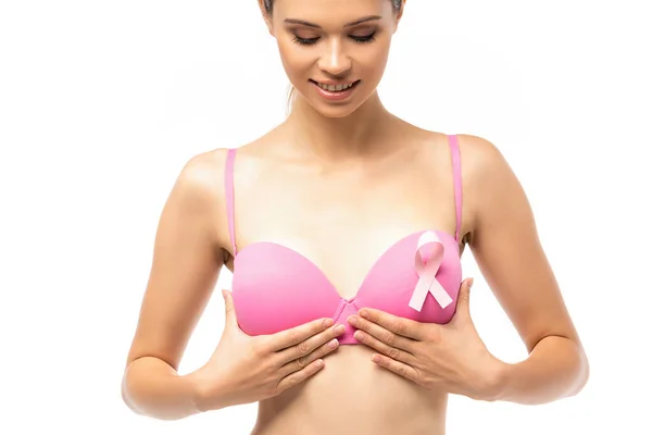 Young woman touching pink bra with ribbon of breast cancer awareness isolated on white — Stock Photo
