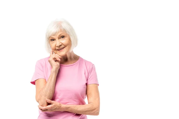 Senior woman with finger near cheek looking at camera isolated on white, breast cancer concept — Stock Photo