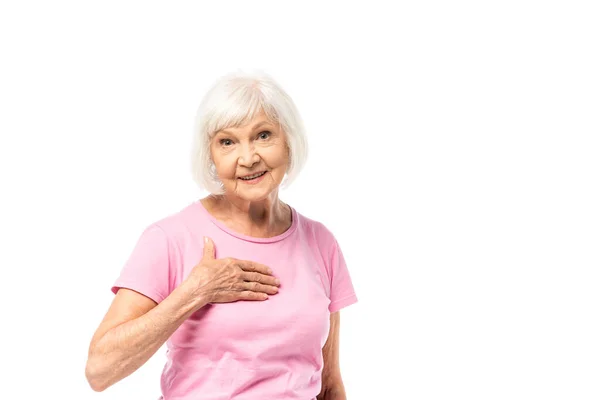 Donna anziana che guarda la fotocamera mentre tocca il petto isolato sul bianco, concetto di cancro al seno — Foto stock