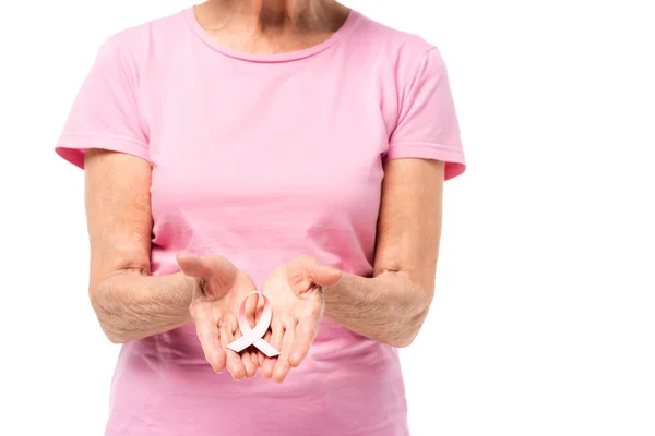 Vue recadrée de la femme âgée montrant un ruban de sensibilisation au cancer du sein isolé sur blanc — Photo de stock