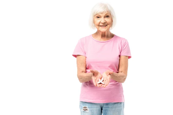 Donna anziana mostrando nastro rosa di consapevolezza del cancro al seno e guardando la fotocamera isolata su bianco — Foto stock