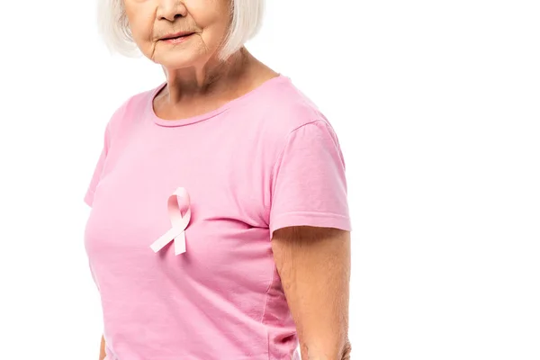 Vista recortada de la mujer anciana con cinta rosa de conciencia de cáncer de mama en la camiseta aislada en blanco - foto de stock